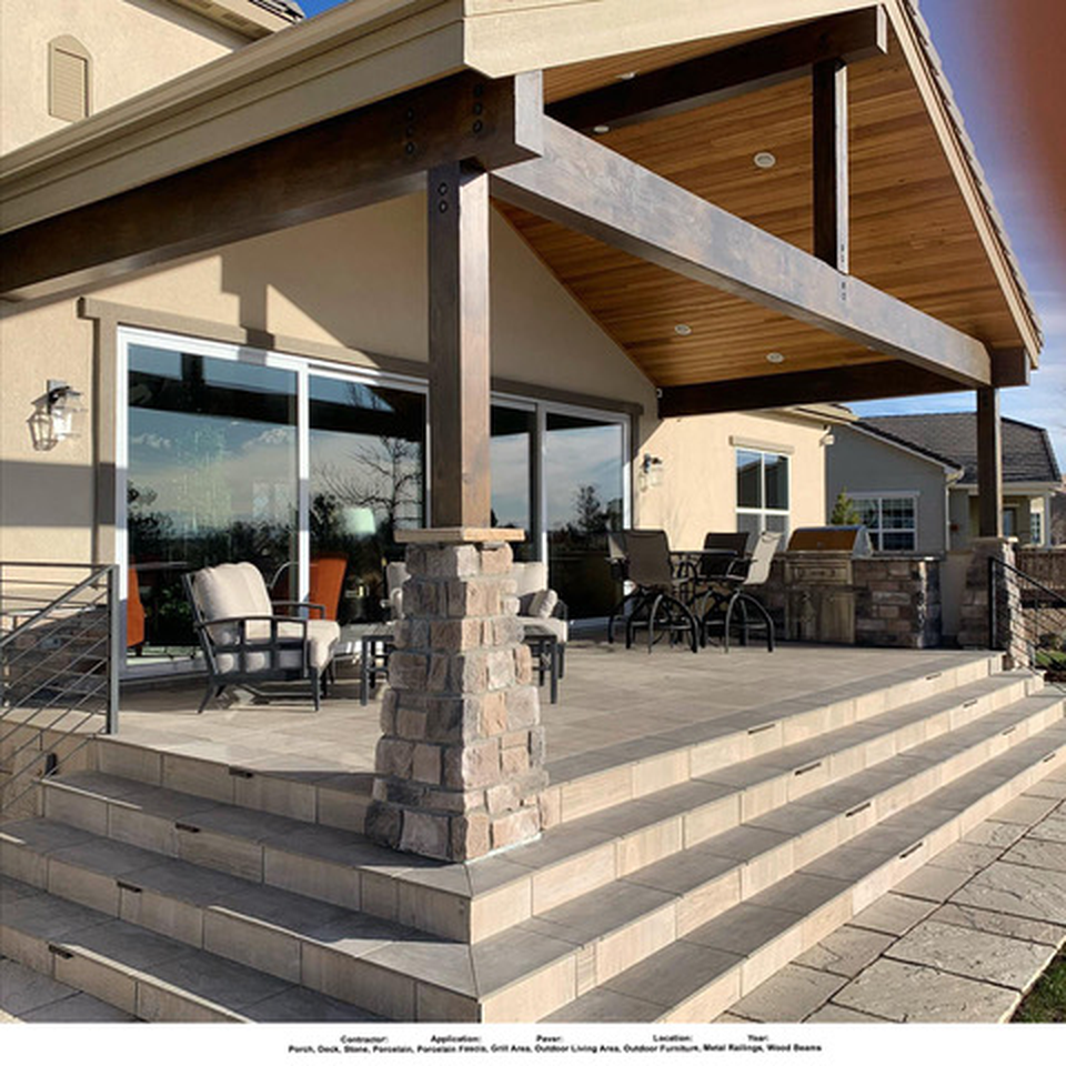 Covered outdoor seating area with a hardscape surface, stone columns and steps.