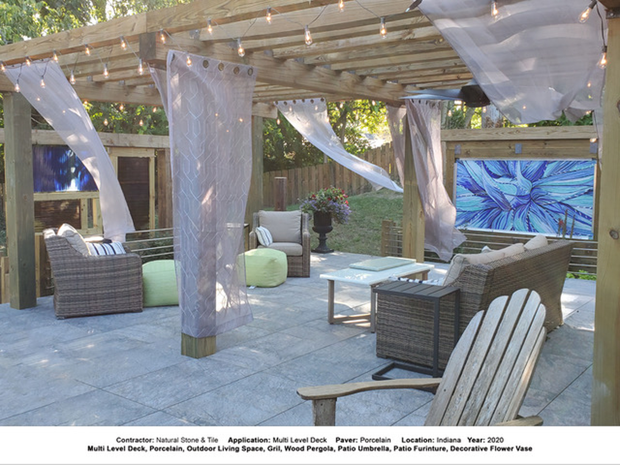 Paver-finished outdoor seating area beneath a pergola with curtains.