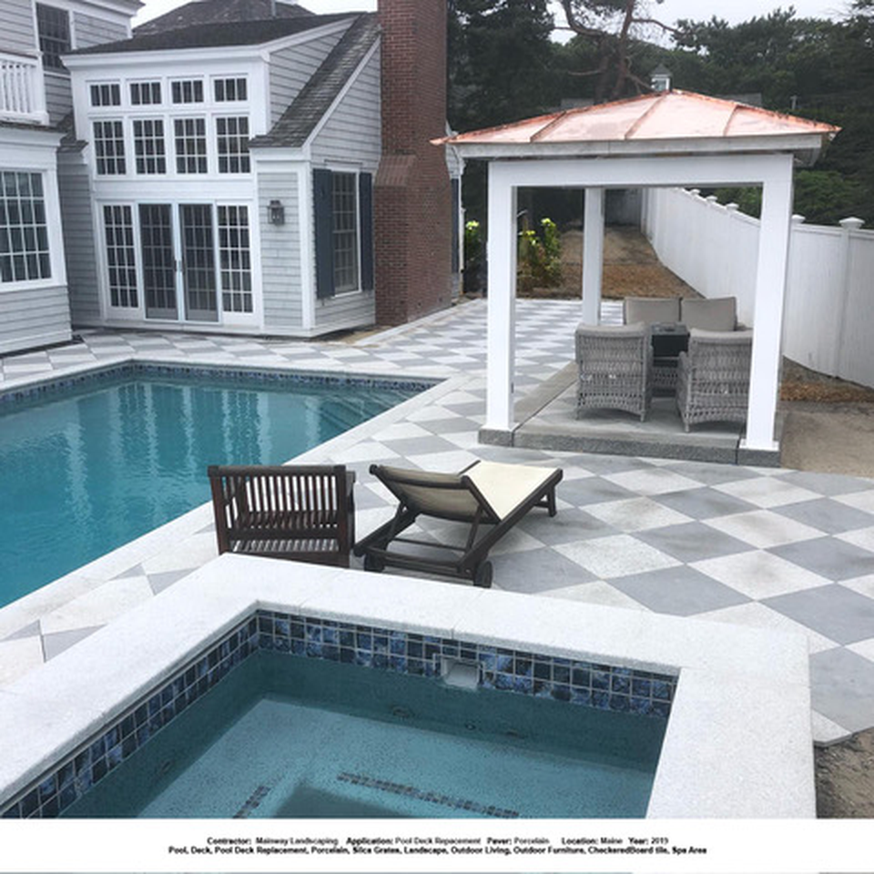 Checkered paver surface beside a swimming pool and covered seating area.